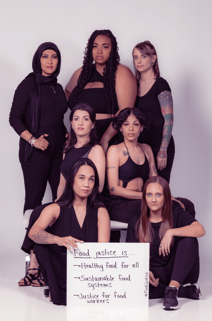 People of different races and backgrounds holding a sign discussing food justice.