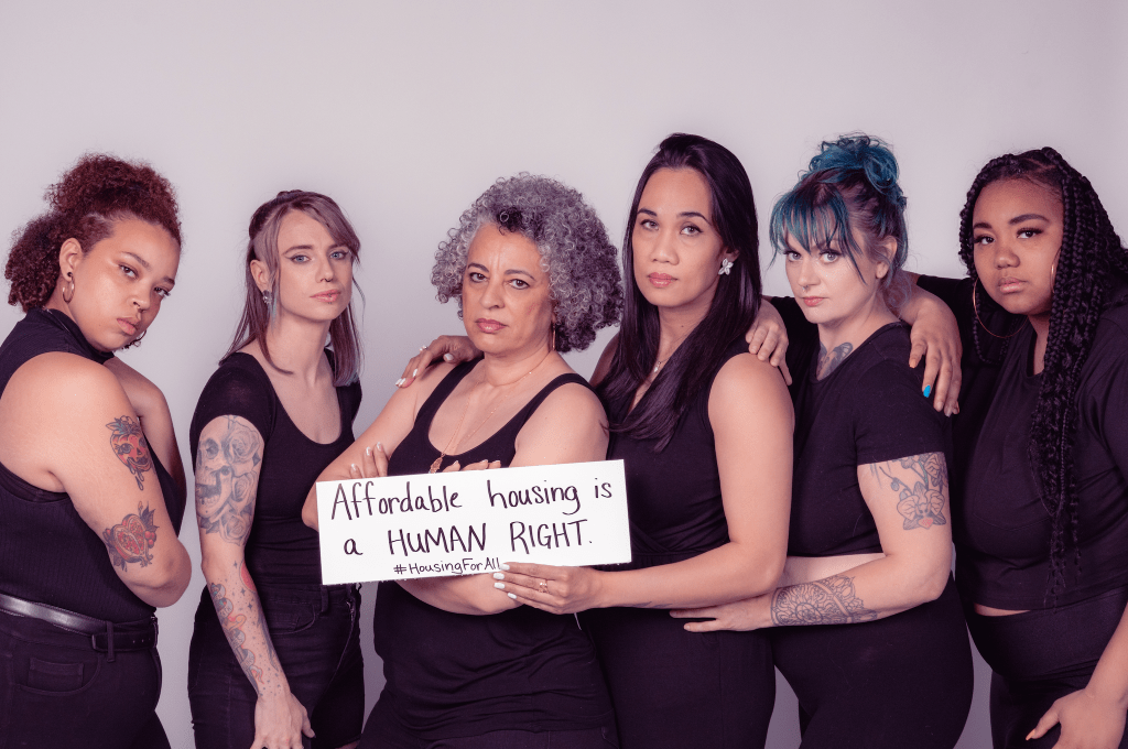 People of different backgrounds and races holding a sign that says "Affordable housing is a human right."